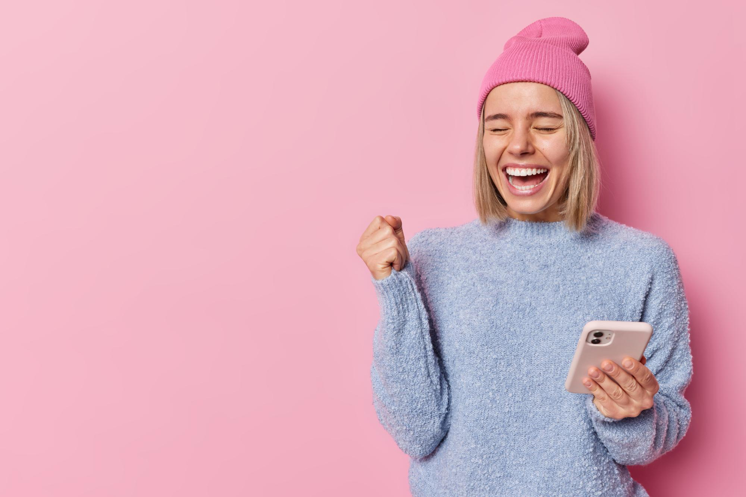 A joyful positive blond woman holding a phone in her hand.