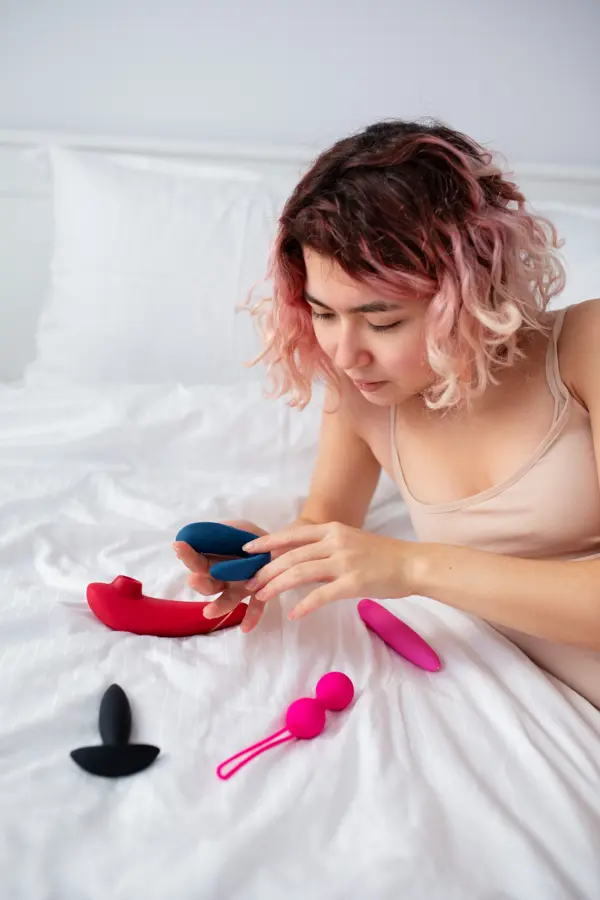An image of a person on the bed with sexual toys.