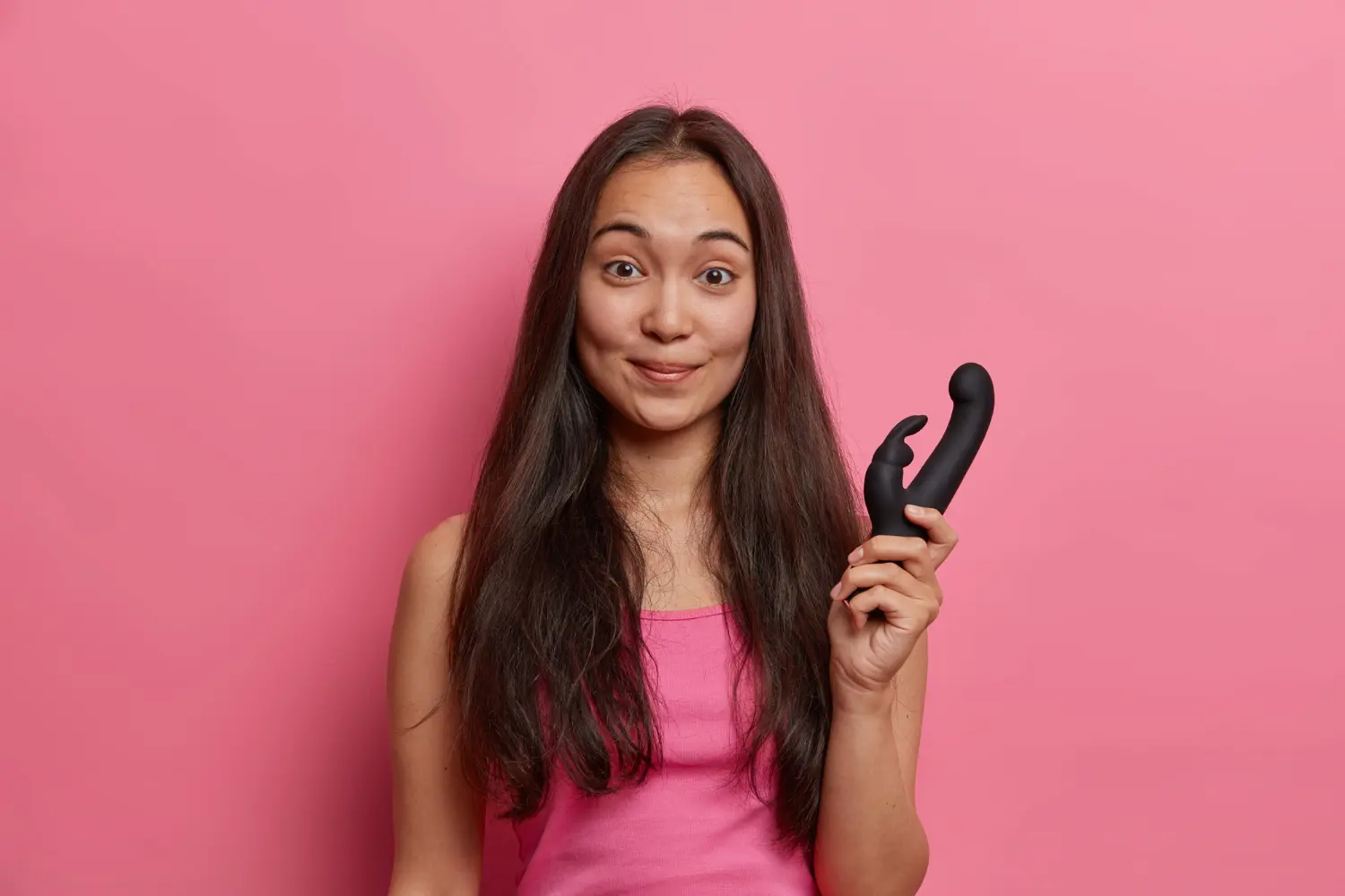 A pleased woman holding a rabbit vibrator in her hand.