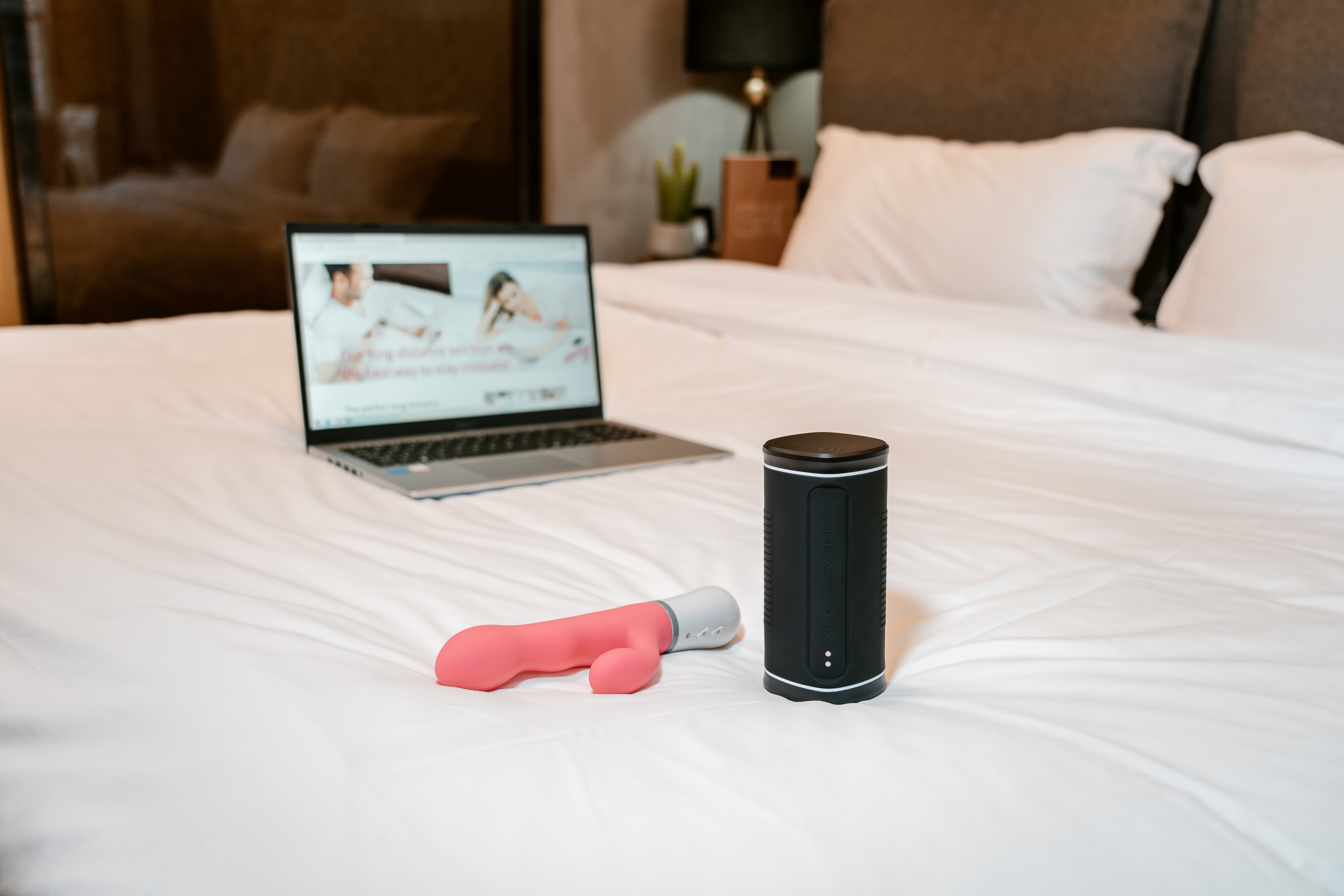 Die Bluetooth-gesteuerten Sexspielzeuge Nora und Calor und ein Laptop auf einem Bett.