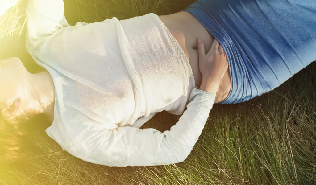 An image of a person lying in the fields with their hand slipping towards their erogenous zone.